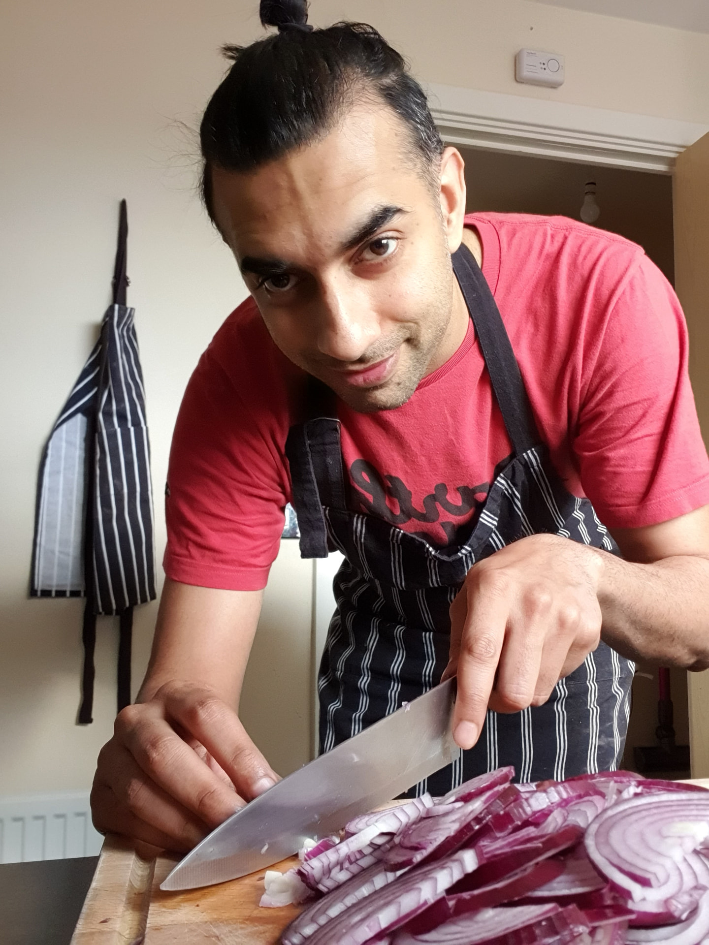 Billie Nabeel Tabassum chopping red onions in his kitchen