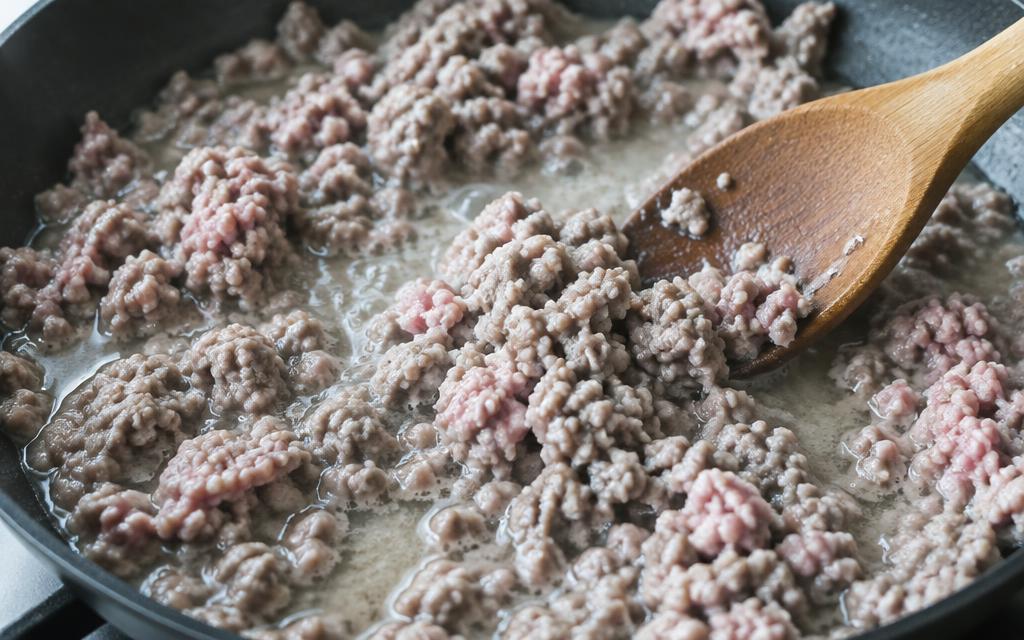 Minced meat still releasing water in the pan, pale and wet looking